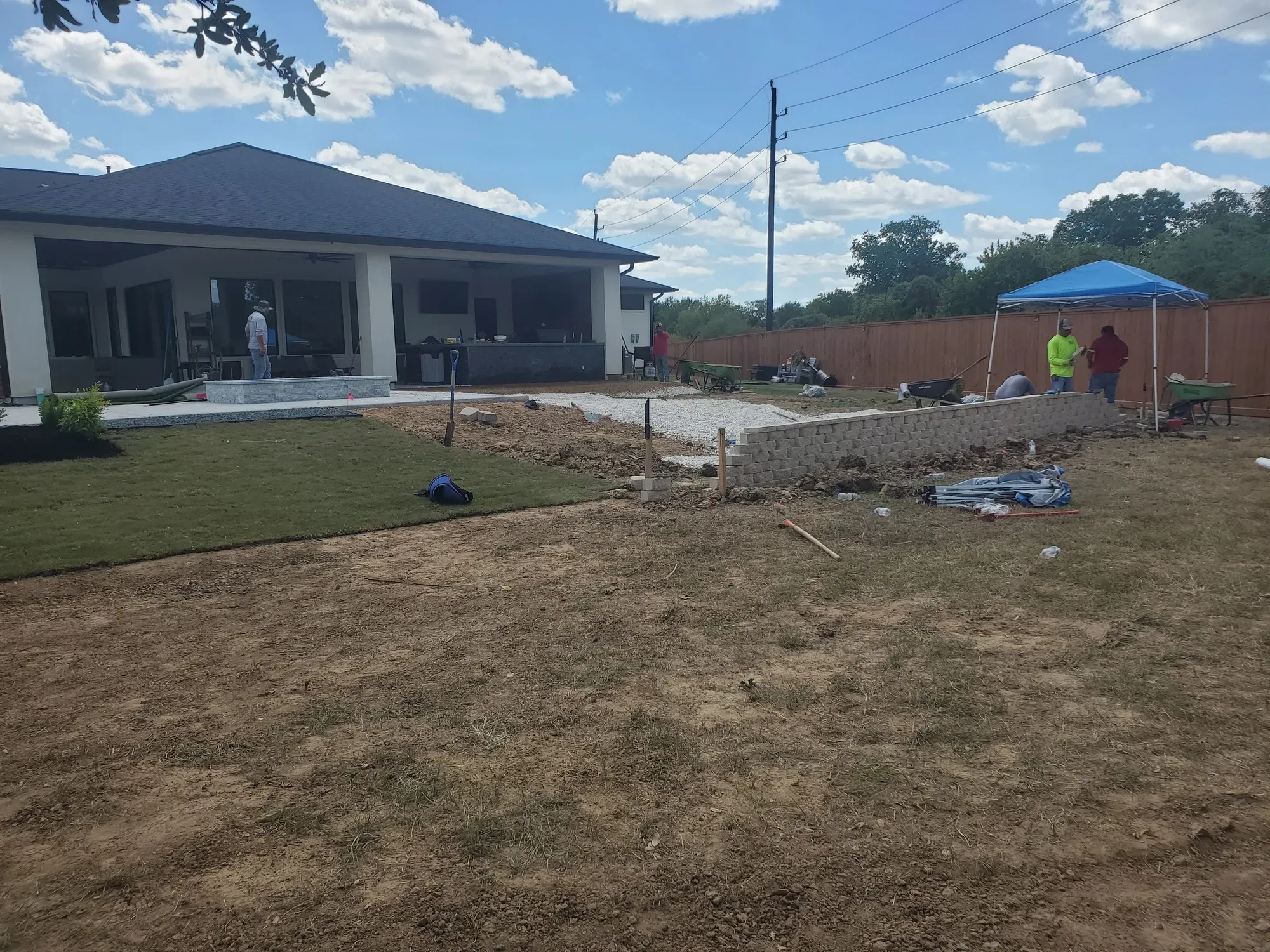 A Houston back yard stripped to bare dirt, with the crew, a wheelbarrow and spoil piles still on site