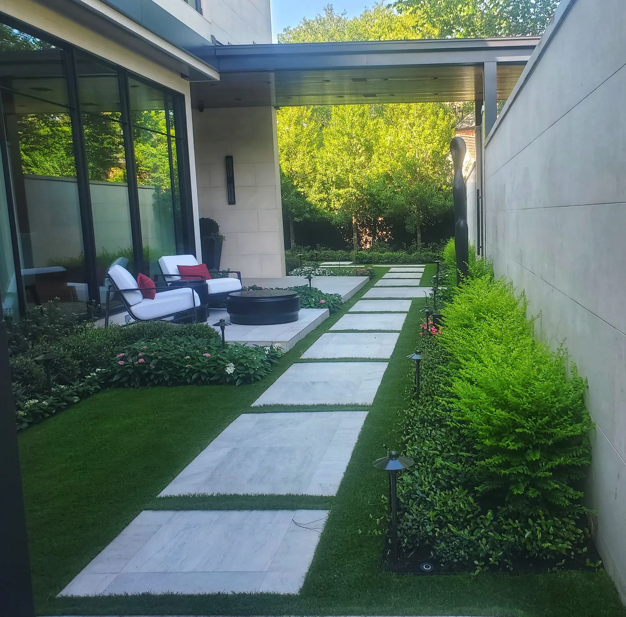 A modern terrace with stone treads set into artificial turf, outdoor seating and clipped planting