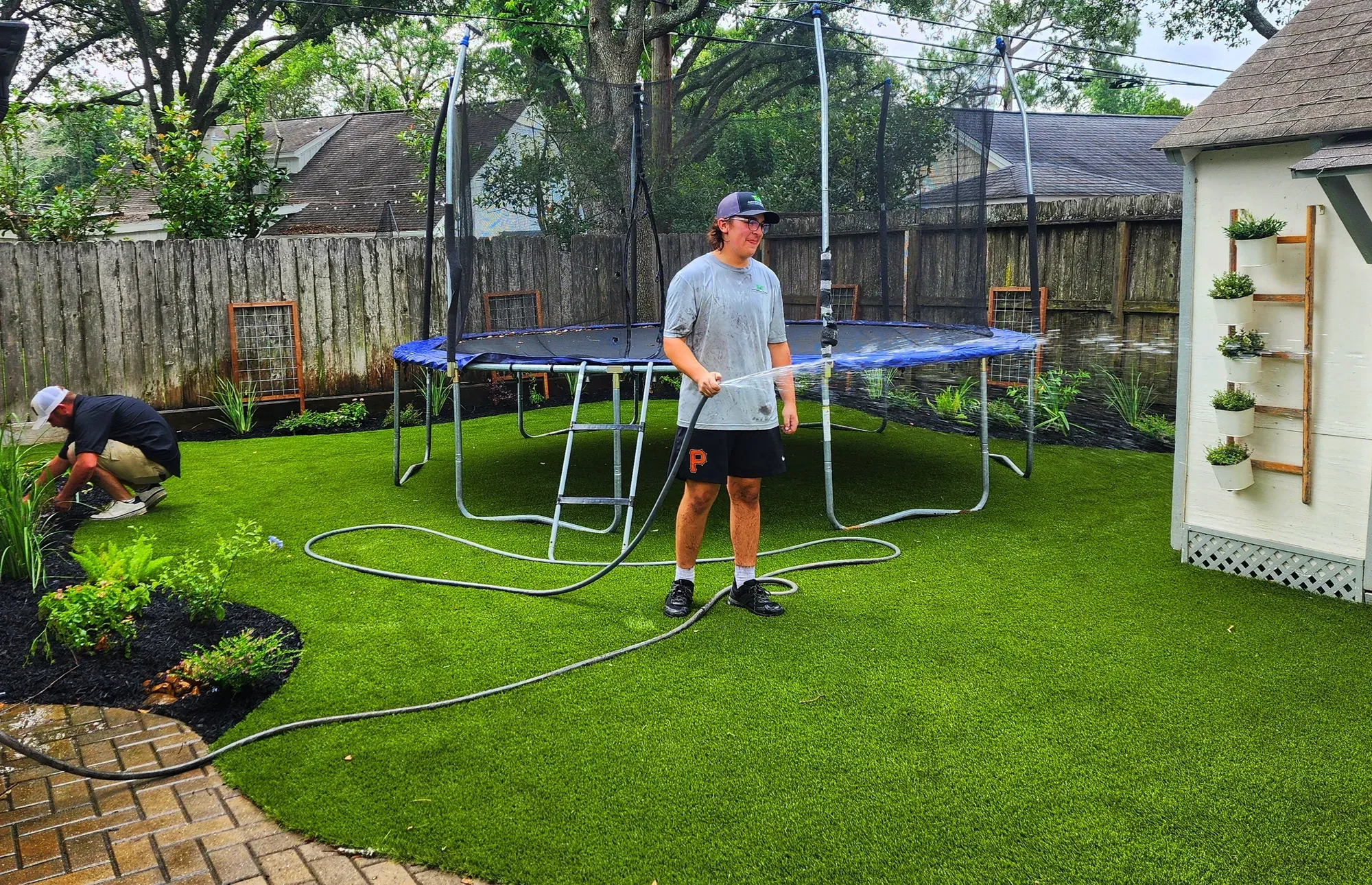 The crew making a finishing pass with a hose over a newly laid back yard lawn